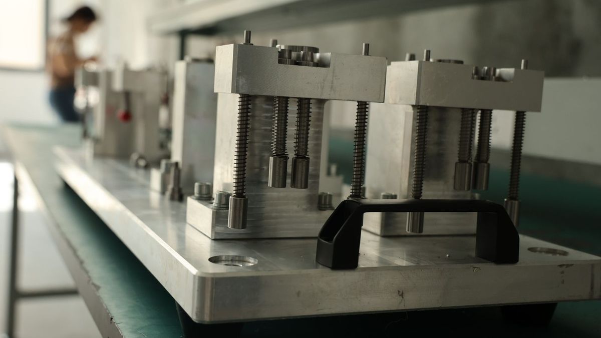 Inspection gauge checking a machined dimension on an aluminum battery box against the drawing