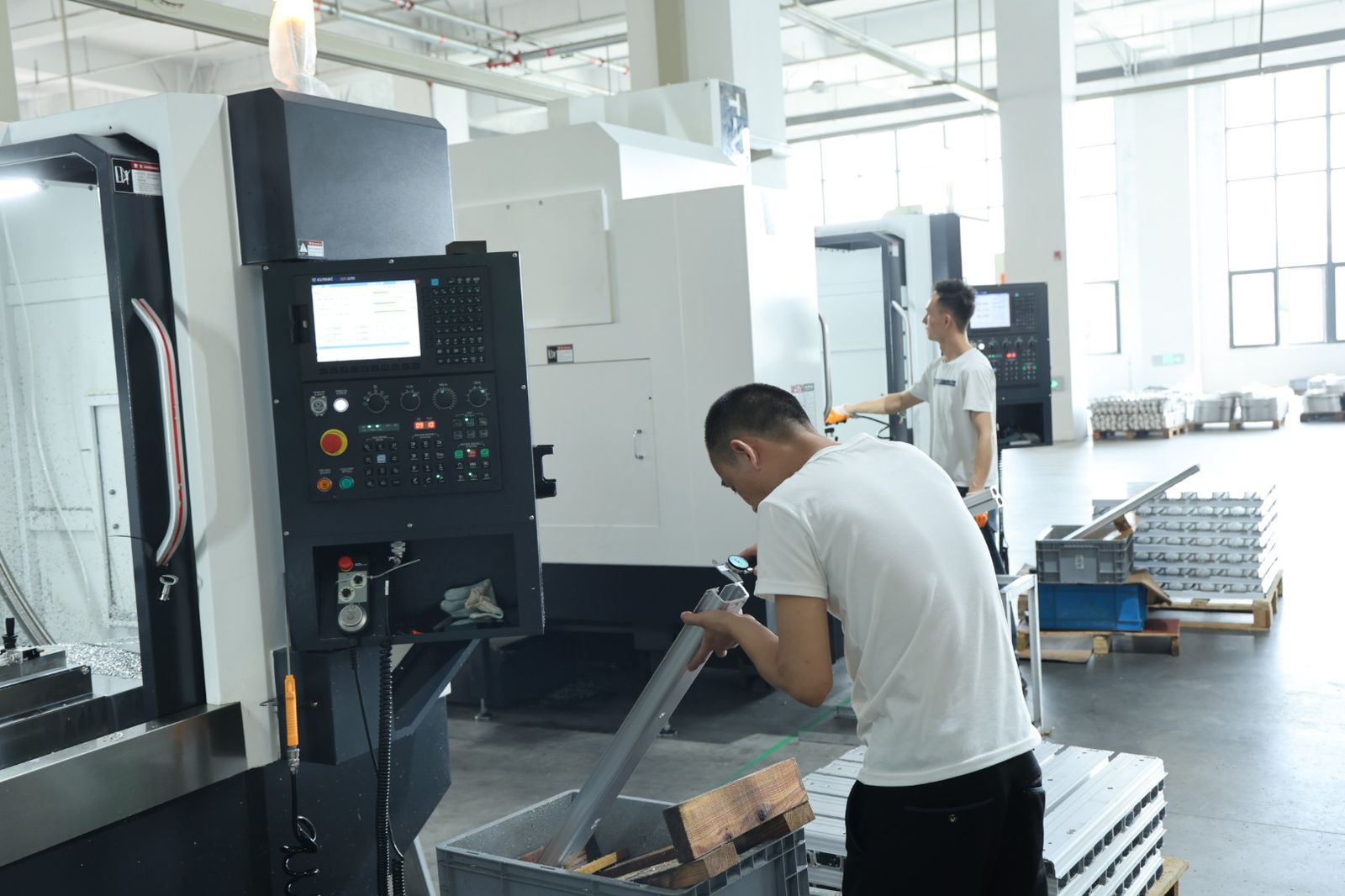 Operator inspecting machined aluminum battery box part in process